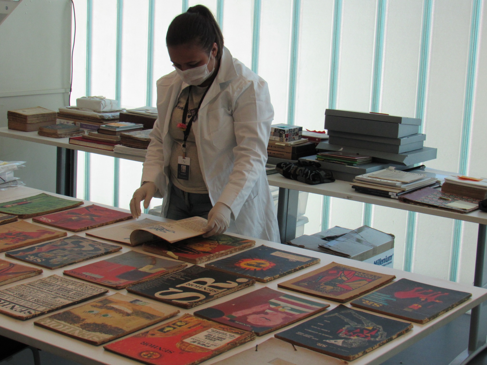 Karen Merlim trabalhando com livros dispostos sobre uma mesa
